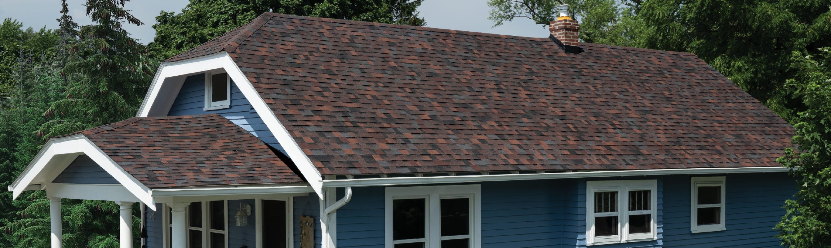 Blue home with white trim and Duration Designer shingles in Bourbon color.