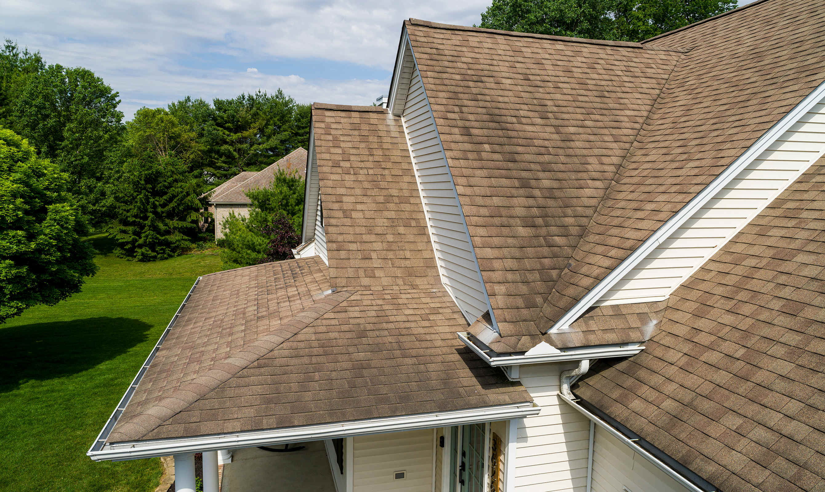 Medium tan rooftop with dark coloration on the shingles. 