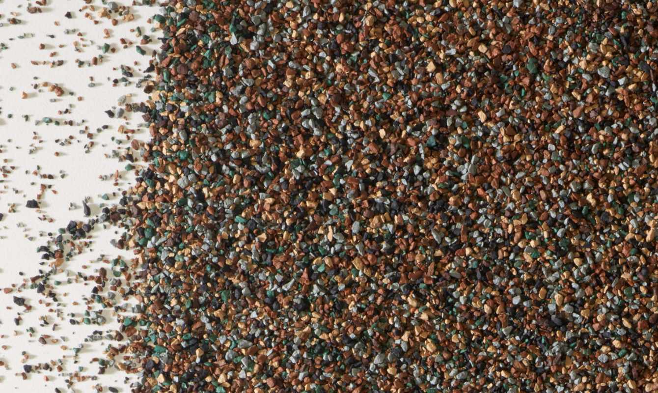 Closeup photo of shingle granules in brown, gray, green, and tan colors