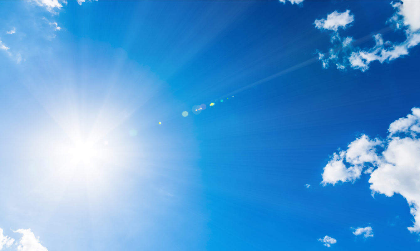 Photo of a bright blue sky with clouds and rays of sun