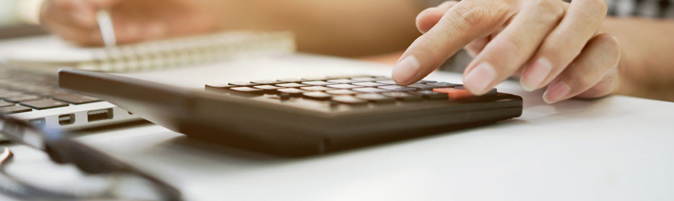 Closeup of a person's hand on a desk using a calculator
