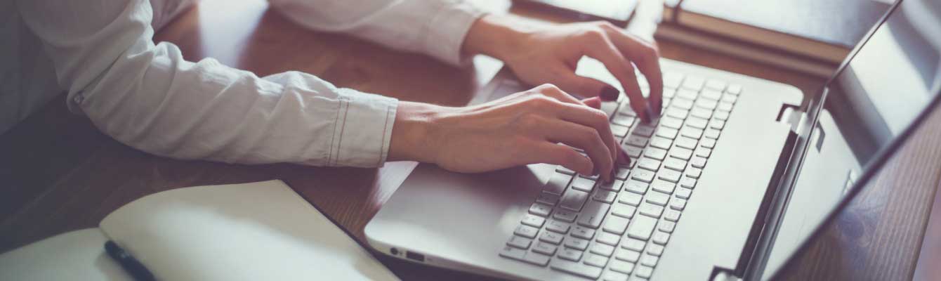 Photo of hands typing on a laptop keyboard
