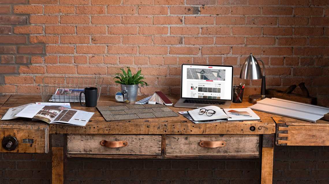 Photo of a desk with shingle colors samples, brochure, and laptop with Owens Corning Pick Your Shingles on the screen