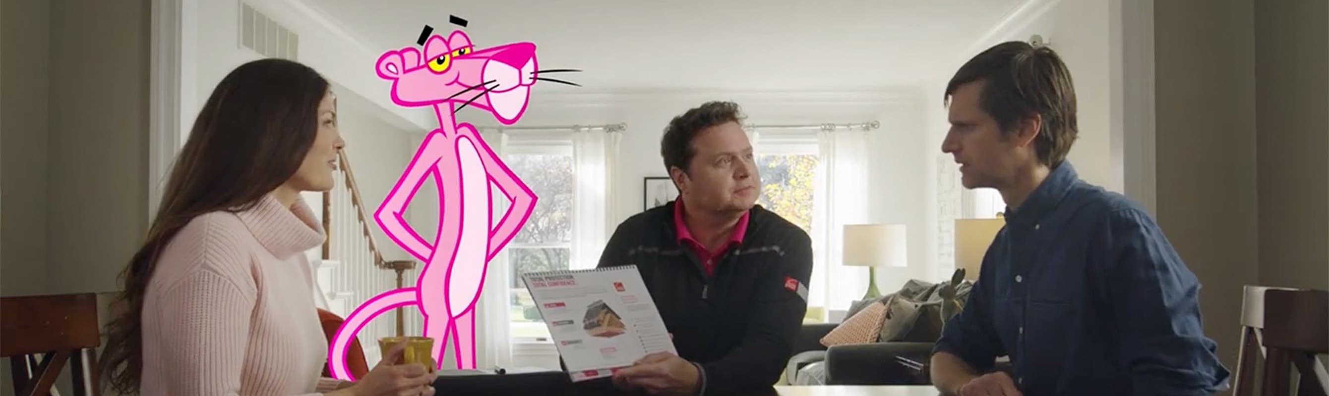 Man and woman meeting with a roofing contractor, sitting at their kitchen table with the Pink Panther standing nearby
