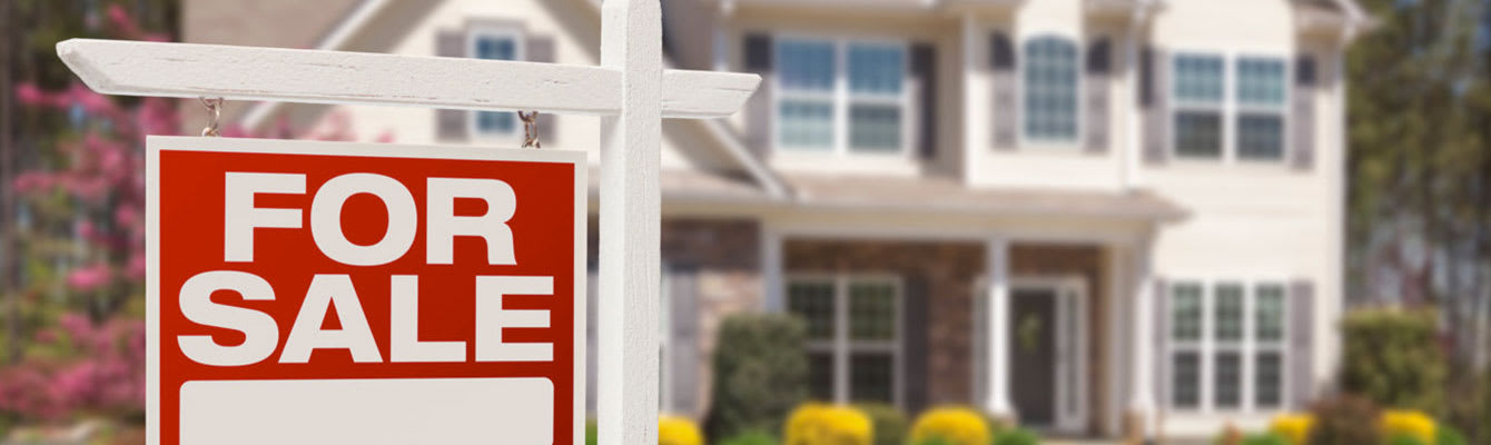 Photo of a red "For Sale" sign in the foreground, with a two story home in the background