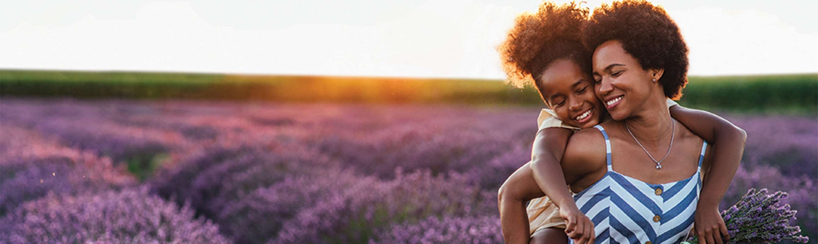 Woman holding child on her back in a field of lavender