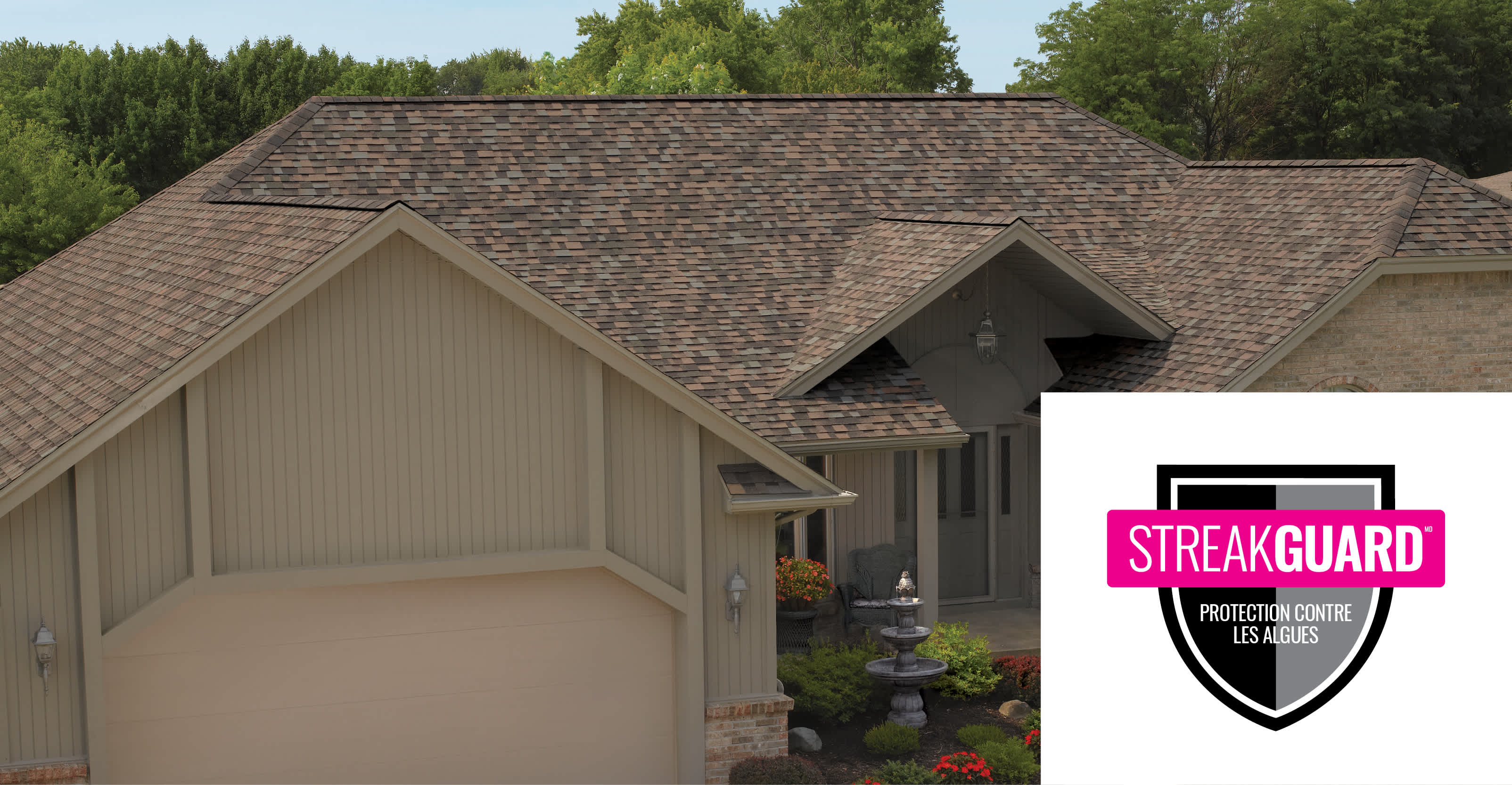 UNE MAISON EN BRIQUES ROUGES AVEC UN TOIT EN BARDEAUX NOIRS ET BRUNS ET LE LOGO STREAKGUARD DANS LE COIN