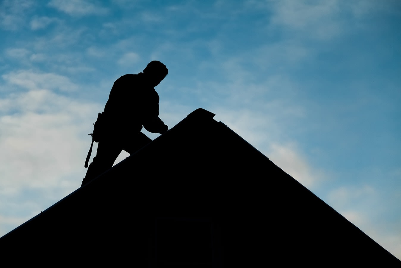 Silhouette of roofer on top of roof