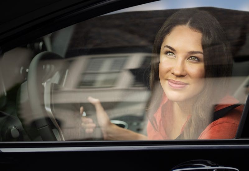 Woman gazing out her car window at a home's roof