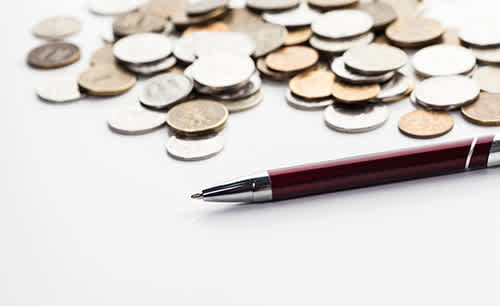 Monetary coins and a pen on a white surface