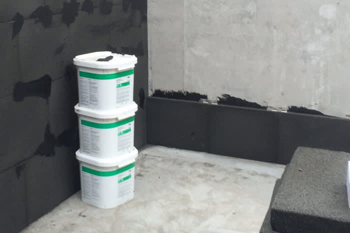 LNG storage tank in the process of having Foamglas insulation installed, buckets of adhesive in foreground