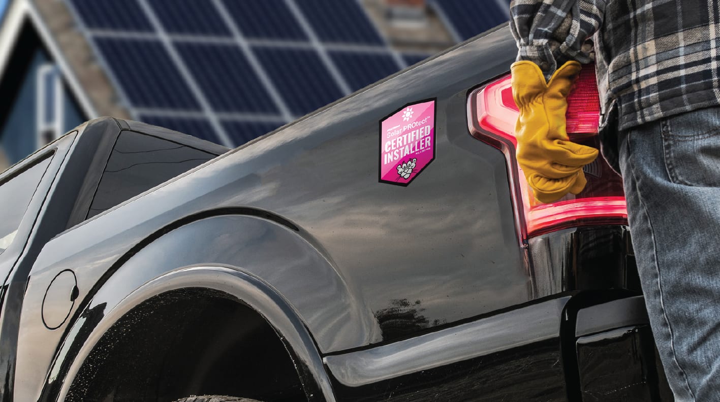 Contratista de pie detrás de una camioneta negra con un gráfico de vinilo de instalador certificado por Owens Corning Solar PROtect en la plataforma de la camioneta.