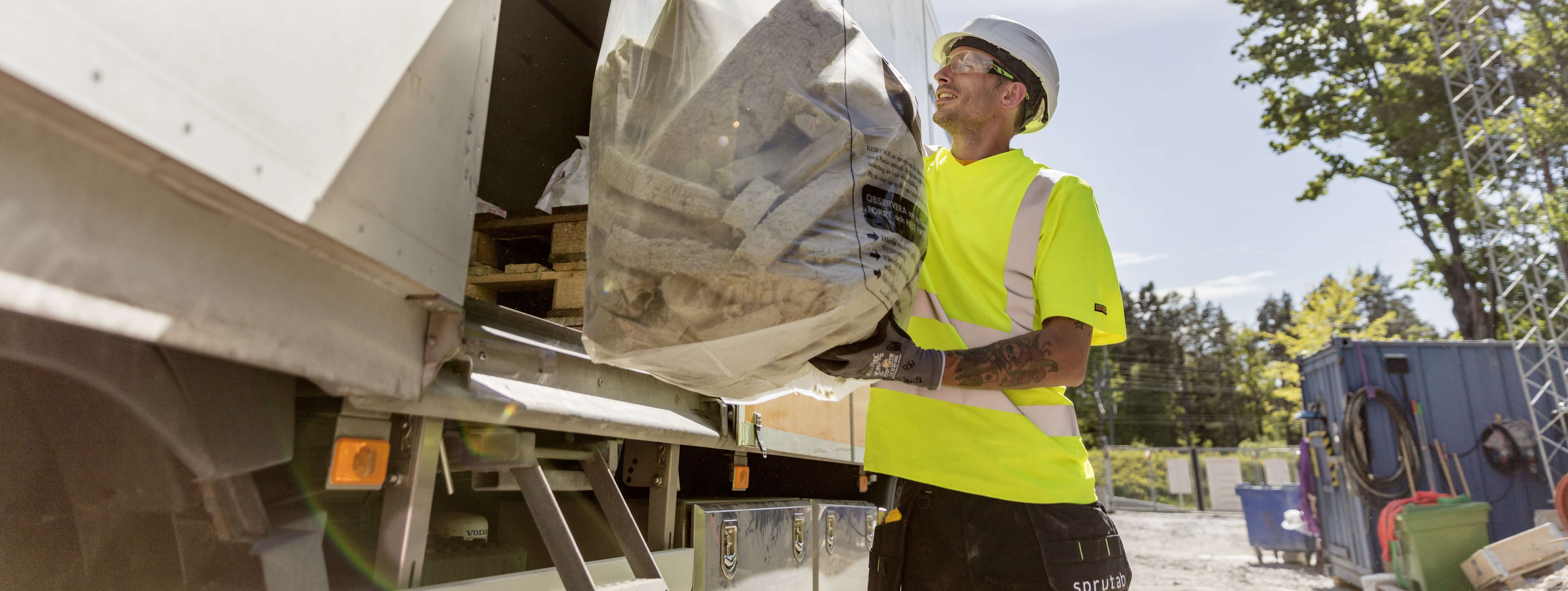 a plant worker is unloading stone wool from a truck to be used in the Rewool program