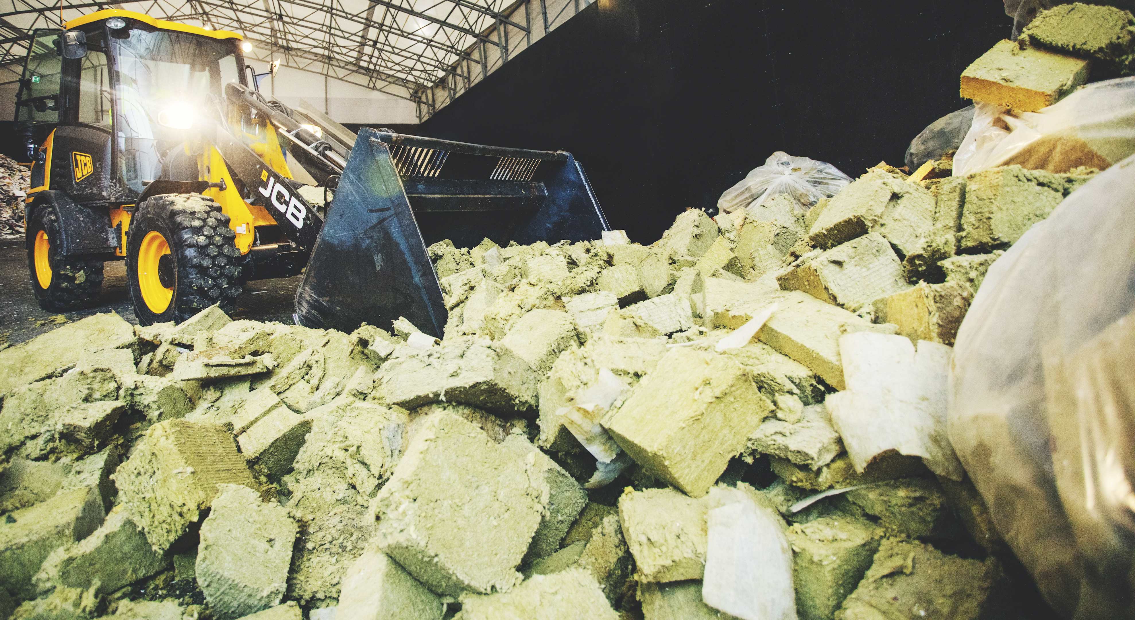 en traktor øser stenuldsaffald