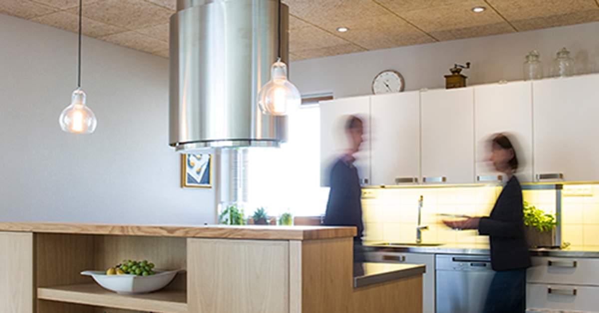 Et køkken med hvide skabe og mennesker sløret.