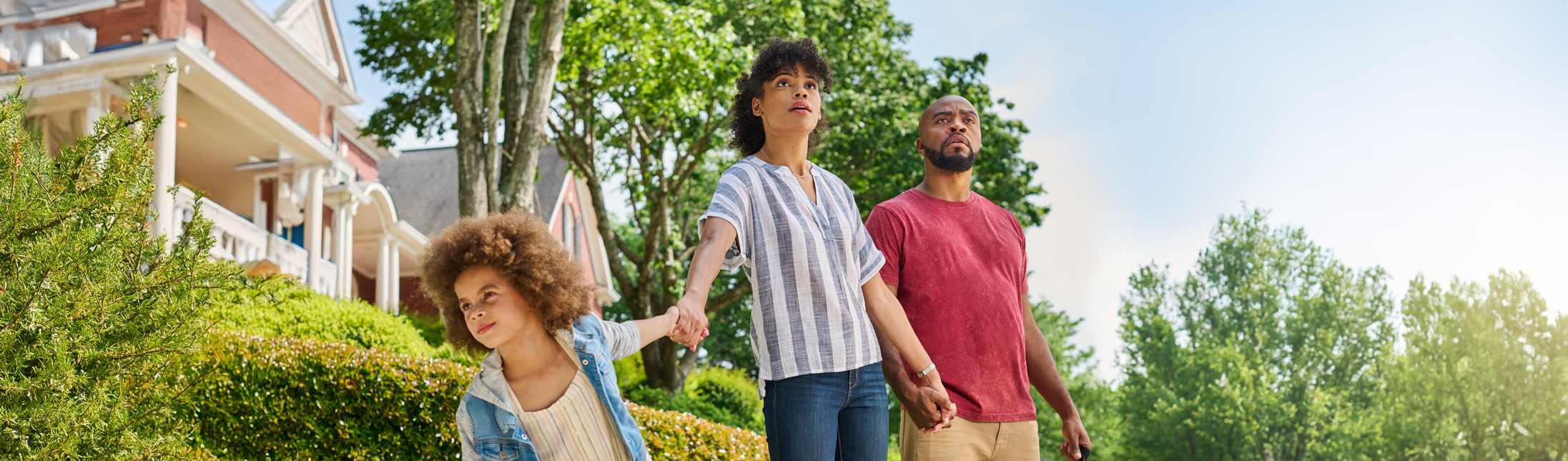 Two parents standing on a street with child gawking up at roofs.