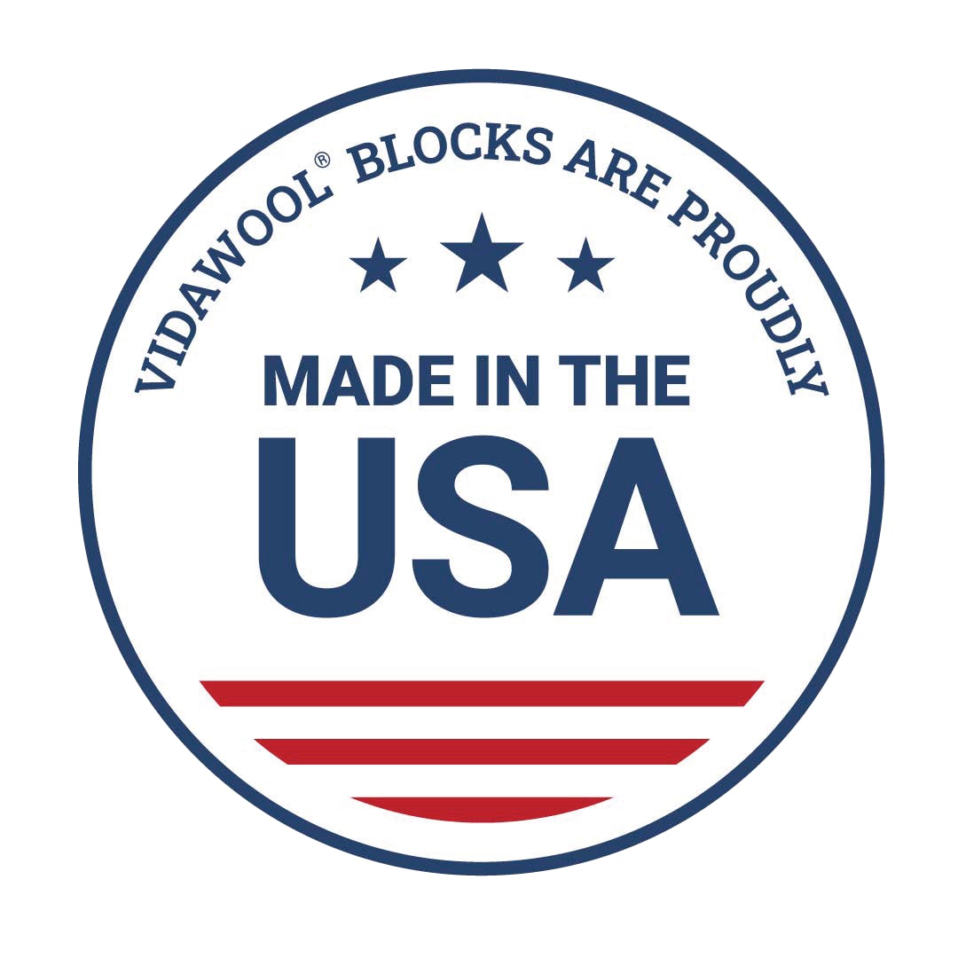 A circular badge with a blue border. Inside the top arc, it reads “VIDAWOOL® BLOCKS ARE PROUDLY” in blue uppercase letters. Below, three blue stars are centered above the bold text “MADE IN THE USA” in blue. At the bottom, there are three red horizontal stripes and a curved red stripe resembling part of the U.S. flag.
