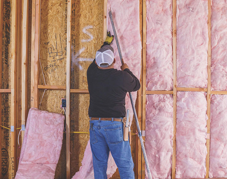 Installer placing pink insulation in wall cavities.