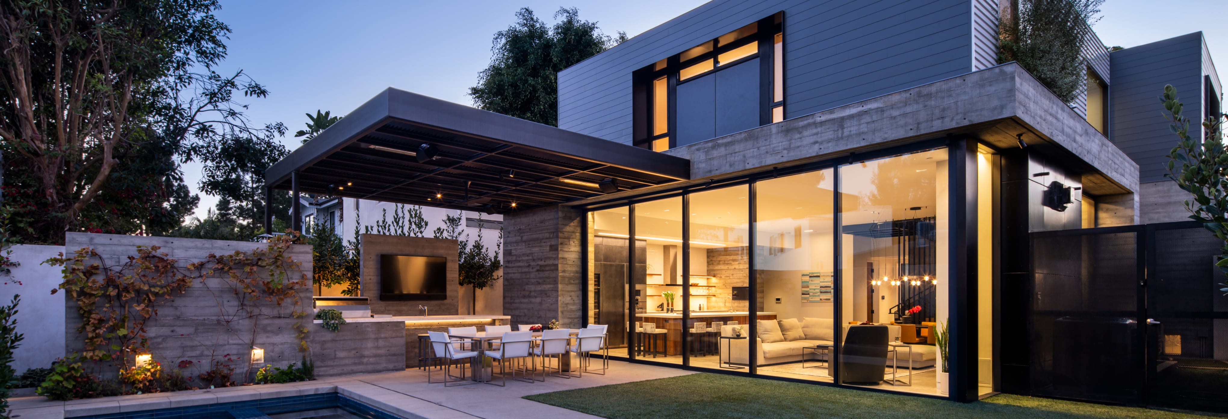 Modern two-stories home with exterior accents, large glass doors, outdoor patio seating.