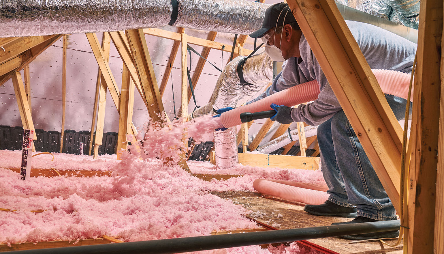 An HVAC contractor installs ProCat® loosefill insulation in an attic