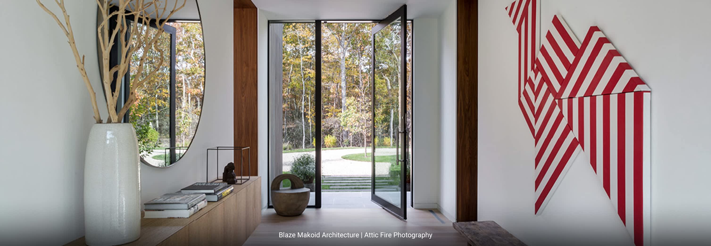 Contemporary entry to modern home with minimalist design, white interior walls and floor-to-ceiling glass doors, bauhaus artwork