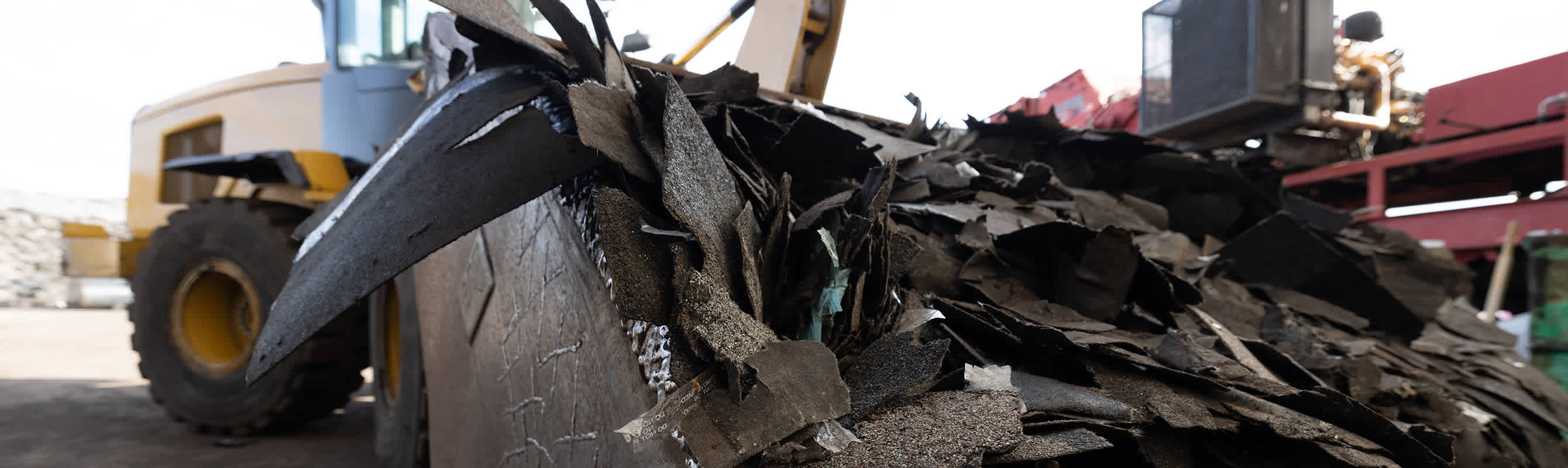 Bulldozer with a load of torn off asphalt shingles for recycling..