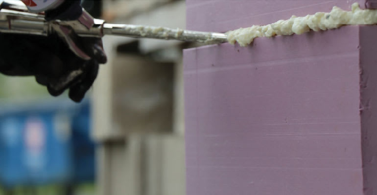Photo of a gloved hand using Owens Corning® ProPink ComfortSeal™ Gun Foam Sealant
