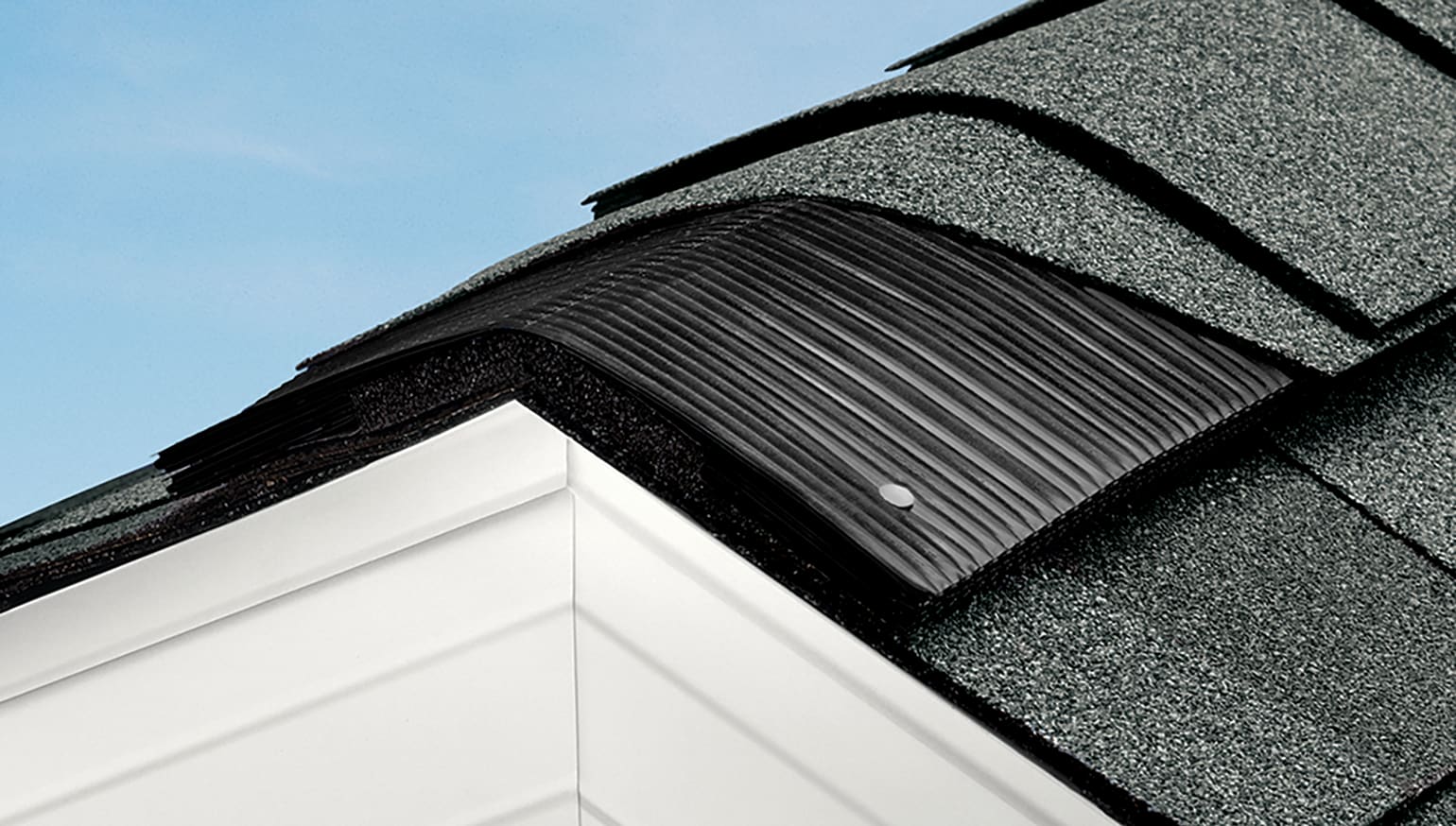 Roof ridge with gray asphalt shingles cut away to expose the VentSure ridge vent.