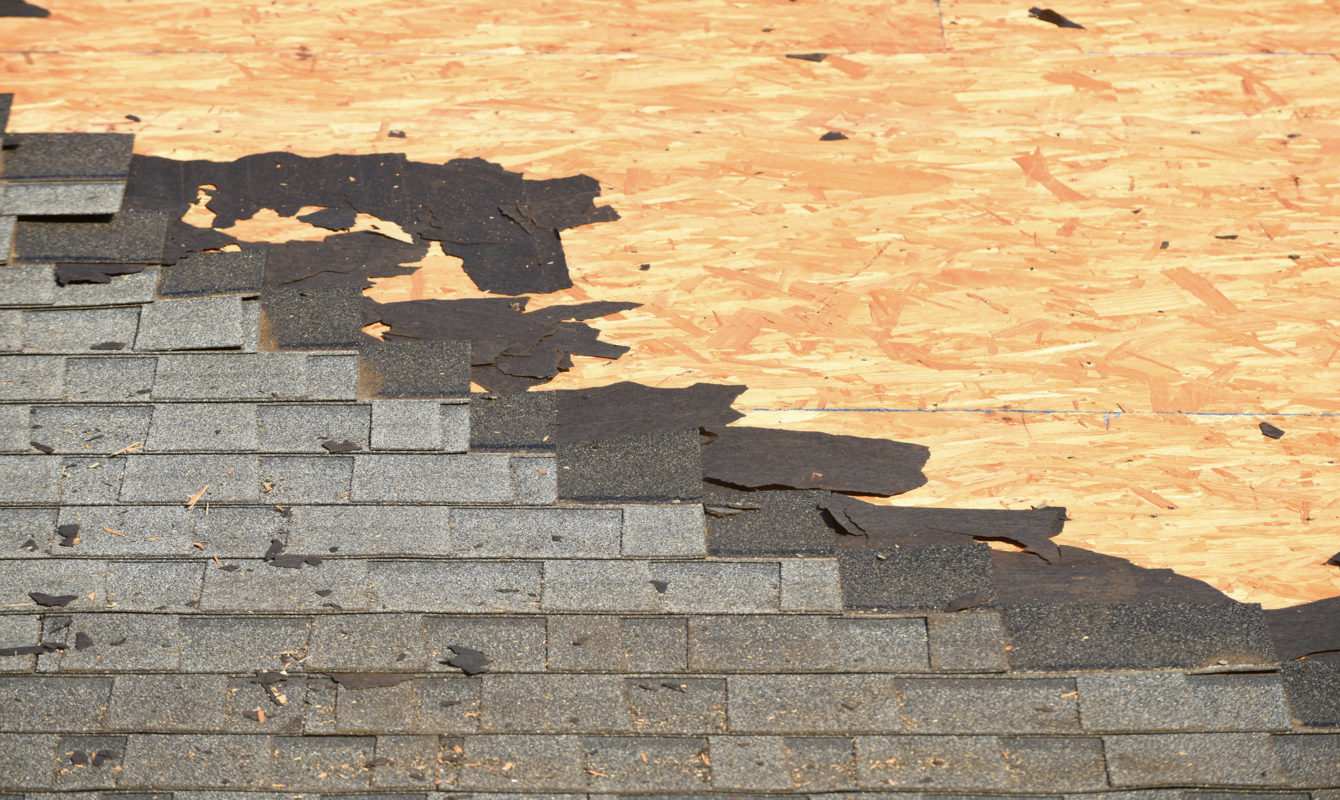 Closeup photo of a roof with old shingles being torn off