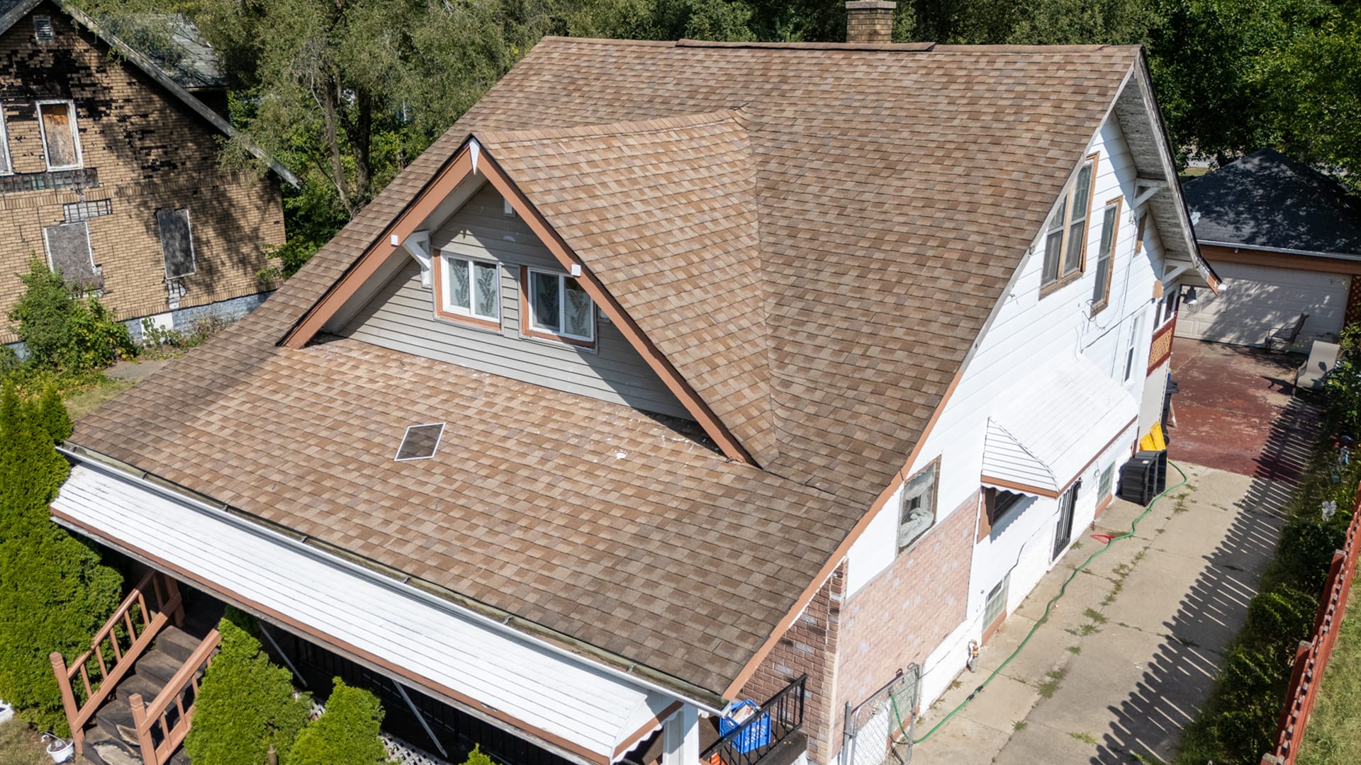 White home with moderately damaged old tan shingles.