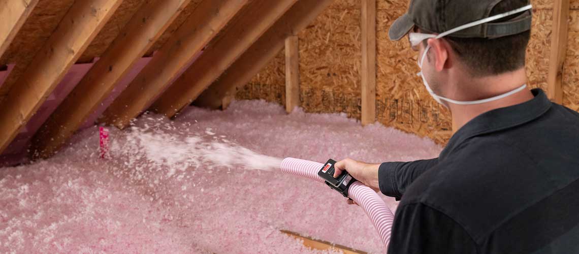 A contractor blowing in loosefill insulation in an attic