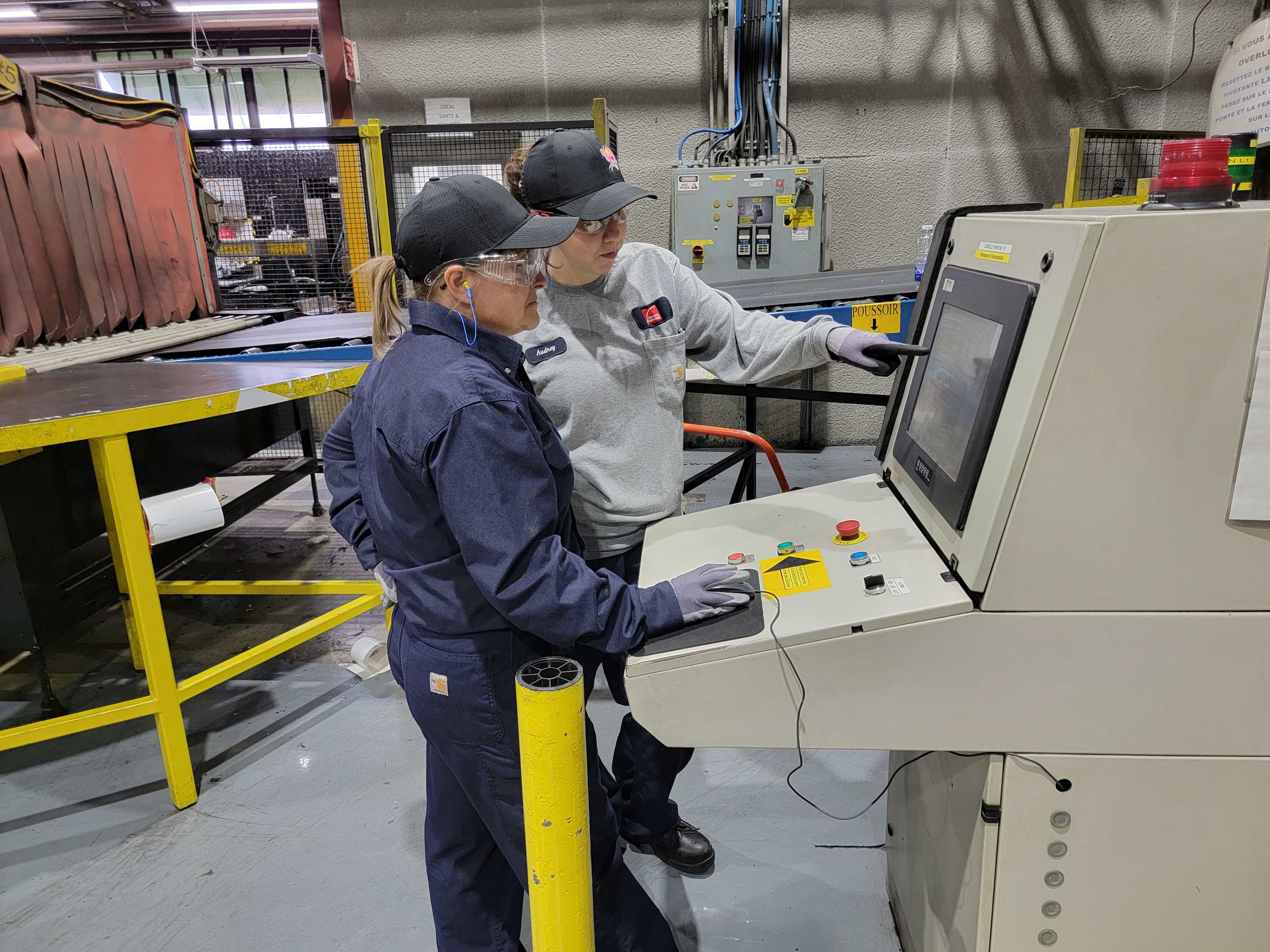 2 people standing at a machine in a factory