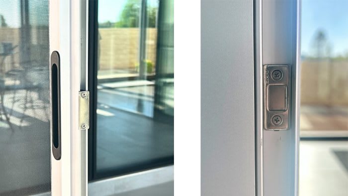 Close-up view of a metal latch strike on a glass door.