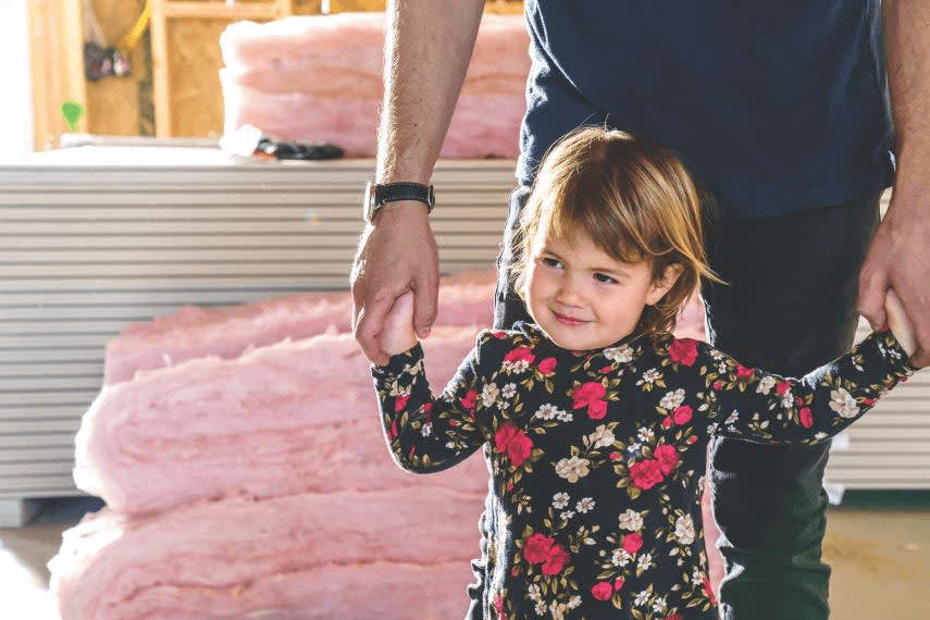 A child holding hands with their parent in a home setting.