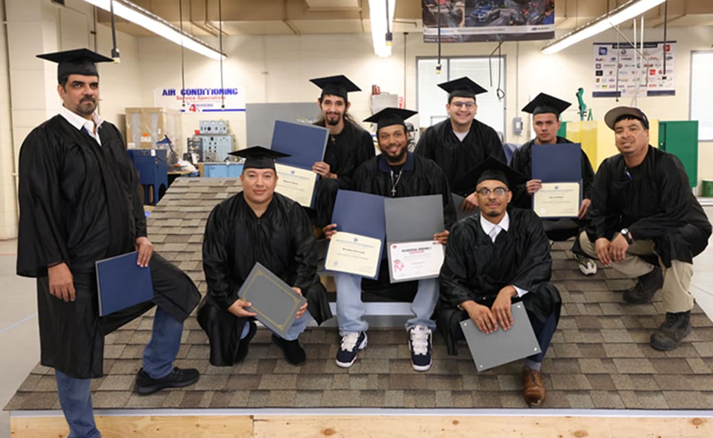 Roofing class graduates standing on a roof model.