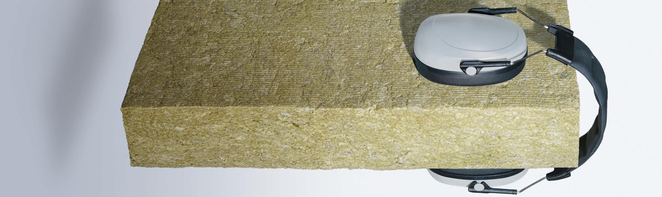 Stone wool insulation material with a pair of headphones, illustrating its use in acoustic insulation.