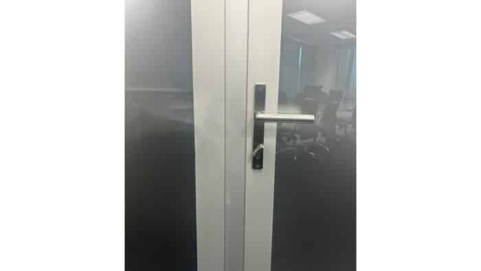 Close up of a glass door with a lever handle in brushed stainless steel.