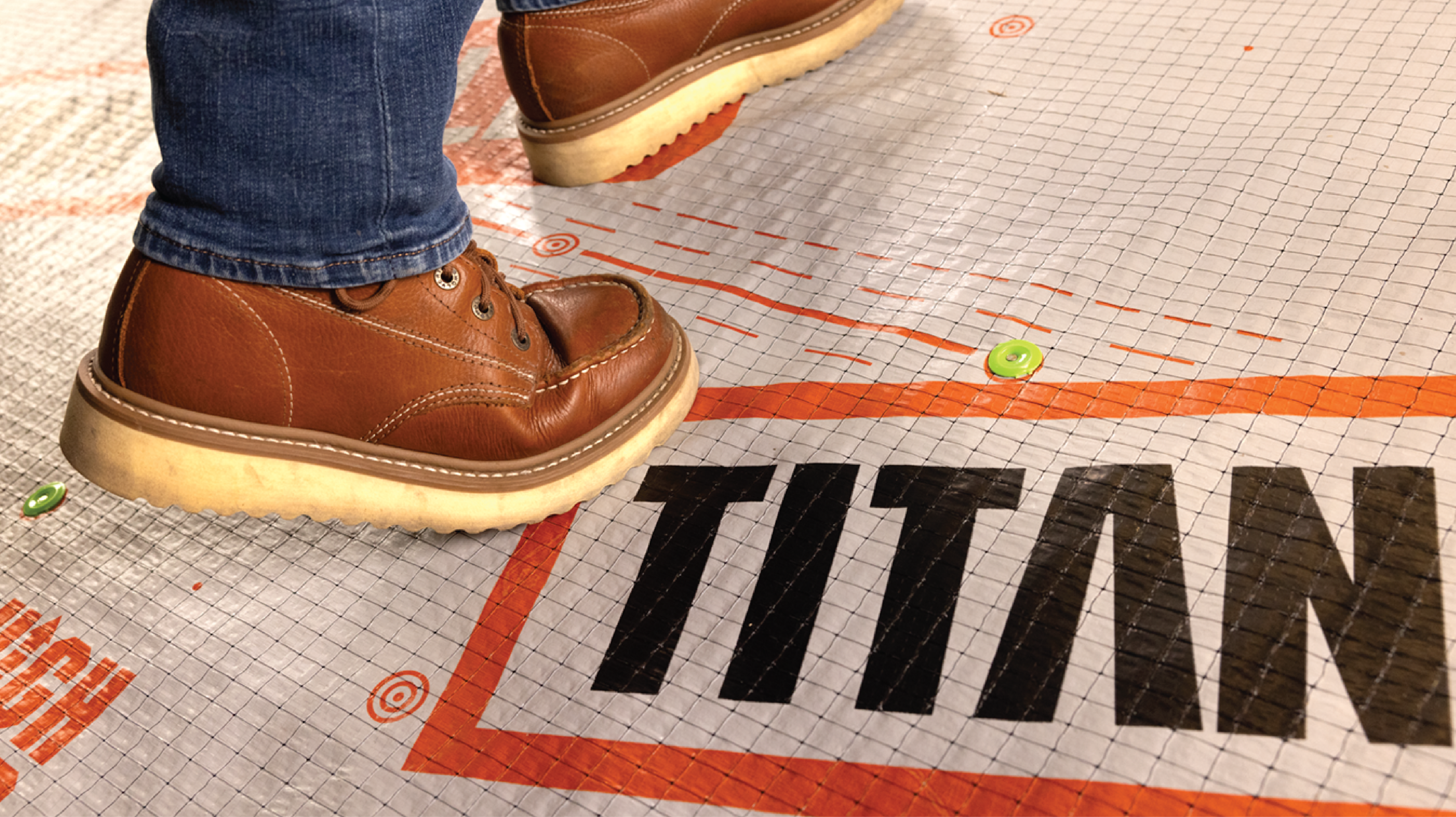 Close-up photo of a contractor standing on a roof holding a roll of Titanium® UDL25 Synthetic Roofing Underlayment