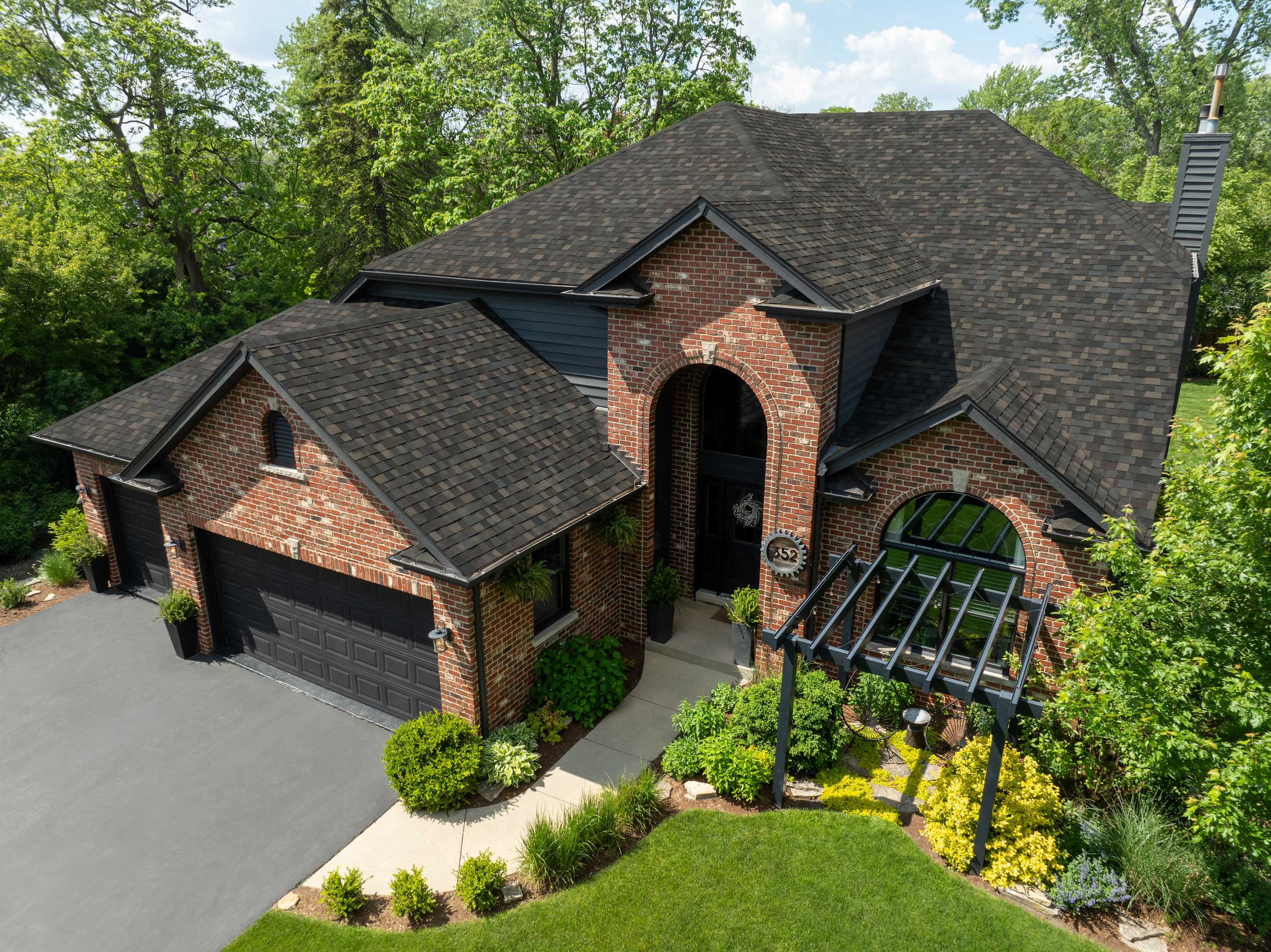 Aerial view of a red brick home with arched entry and a new roof with Owens Corning TruDefinition Duration Black Sable asphalt shingles