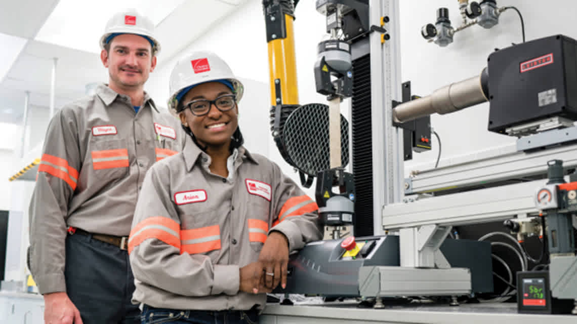 Two Owens Corning employees stand together in a manufacturing factory.