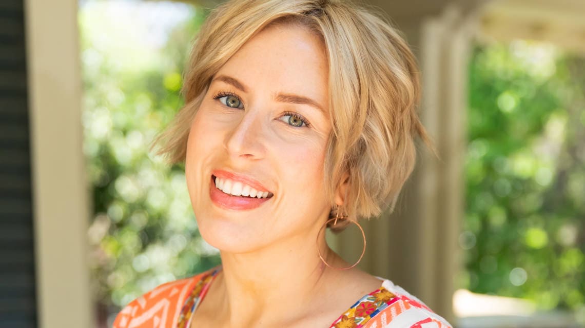 Erin Napier smiling in front of a house